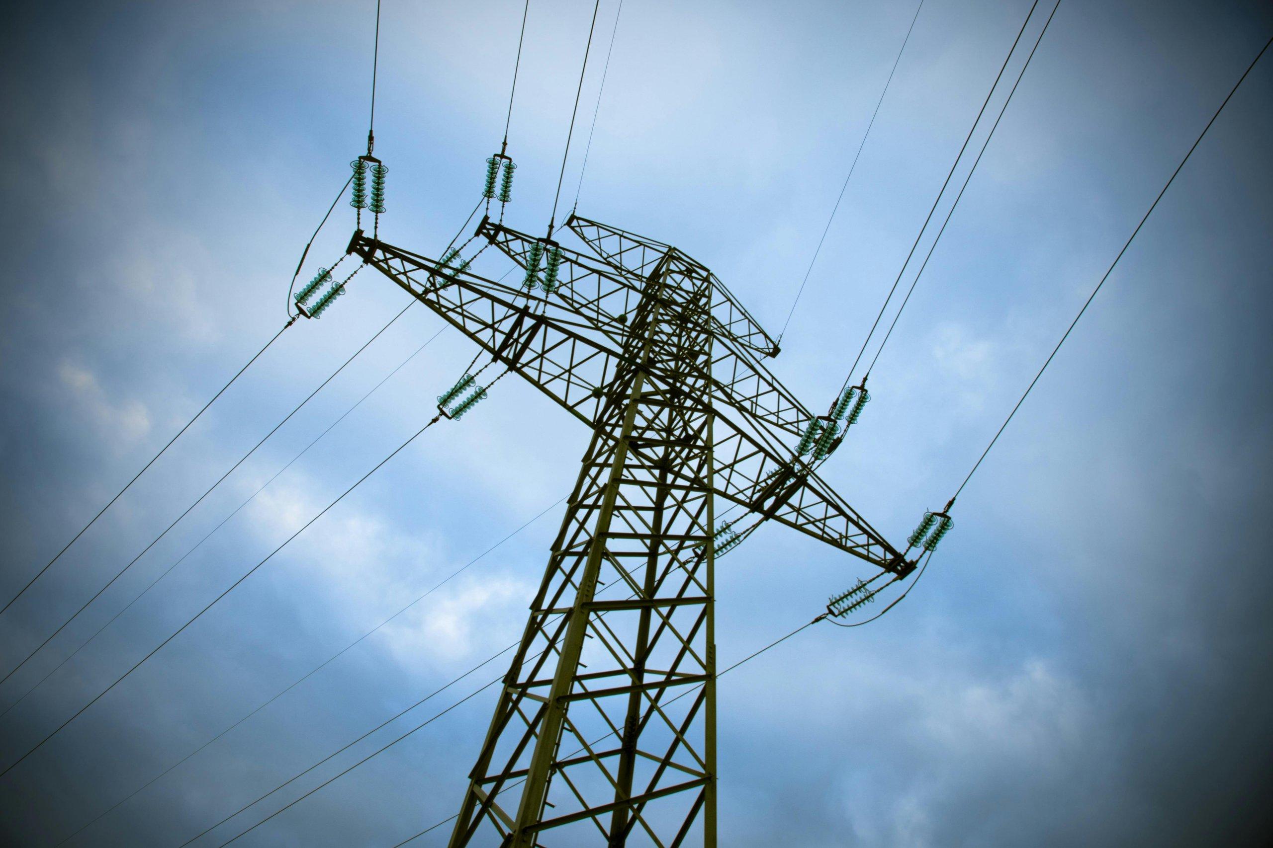 Transmission tower against cloudy sky